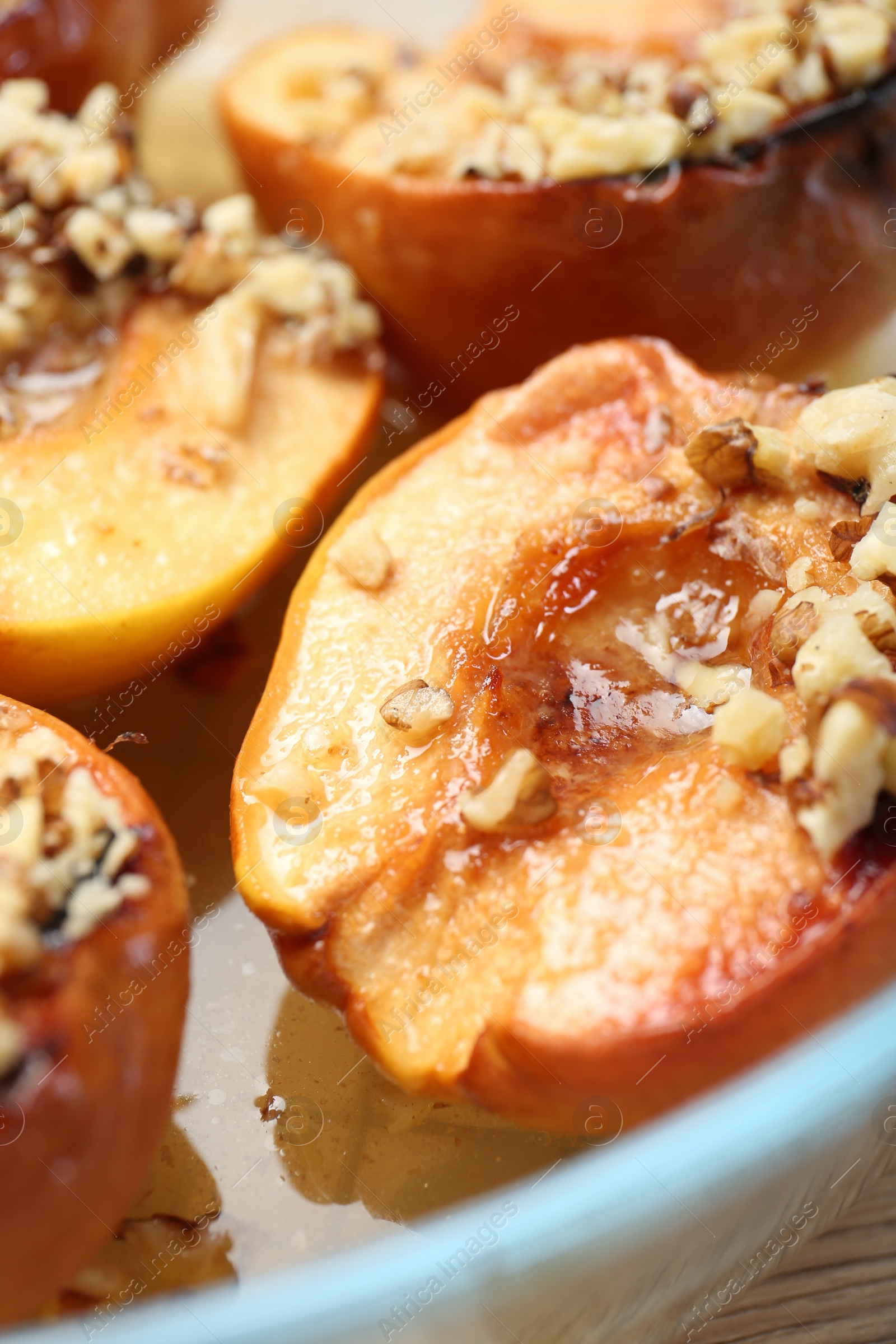 Photo of Delicious baked quinces with nuts and honey in bowl, closeup