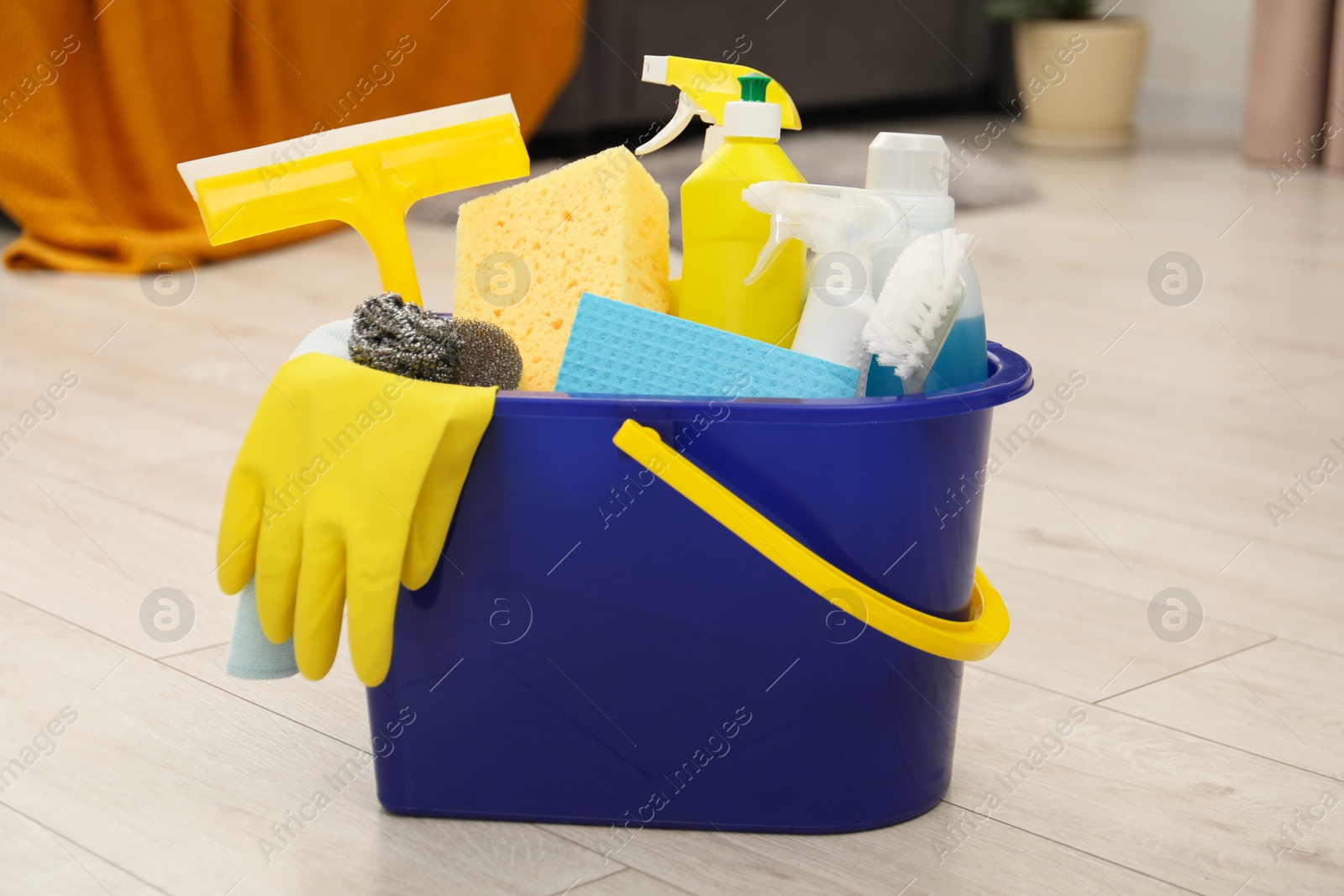 Photo of Different cleaning supplies in bucket on floor at home