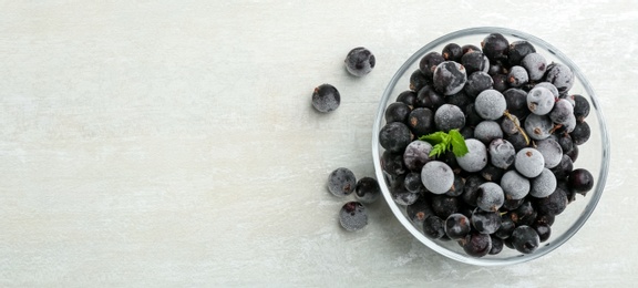 Tasty frozen black currants on white table, flat lay. Space for text