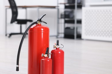 Photo of Fire extinguishers on floor indoors, space for text