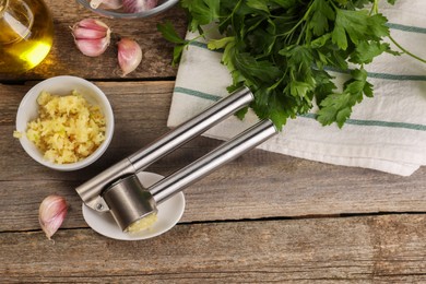 Photo of Garlic press and products on wooden table, flat lay