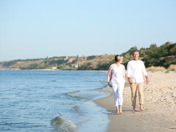 Photo of Happy mature couple walking at beach on sunny day