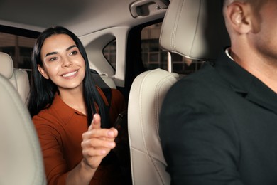 Photo of Young woman and taxi driver in modern car