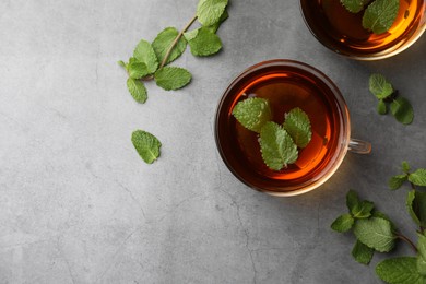 Photo of Cups of aromatic herbal tea with mint on grey table, flat lay. Space for text
