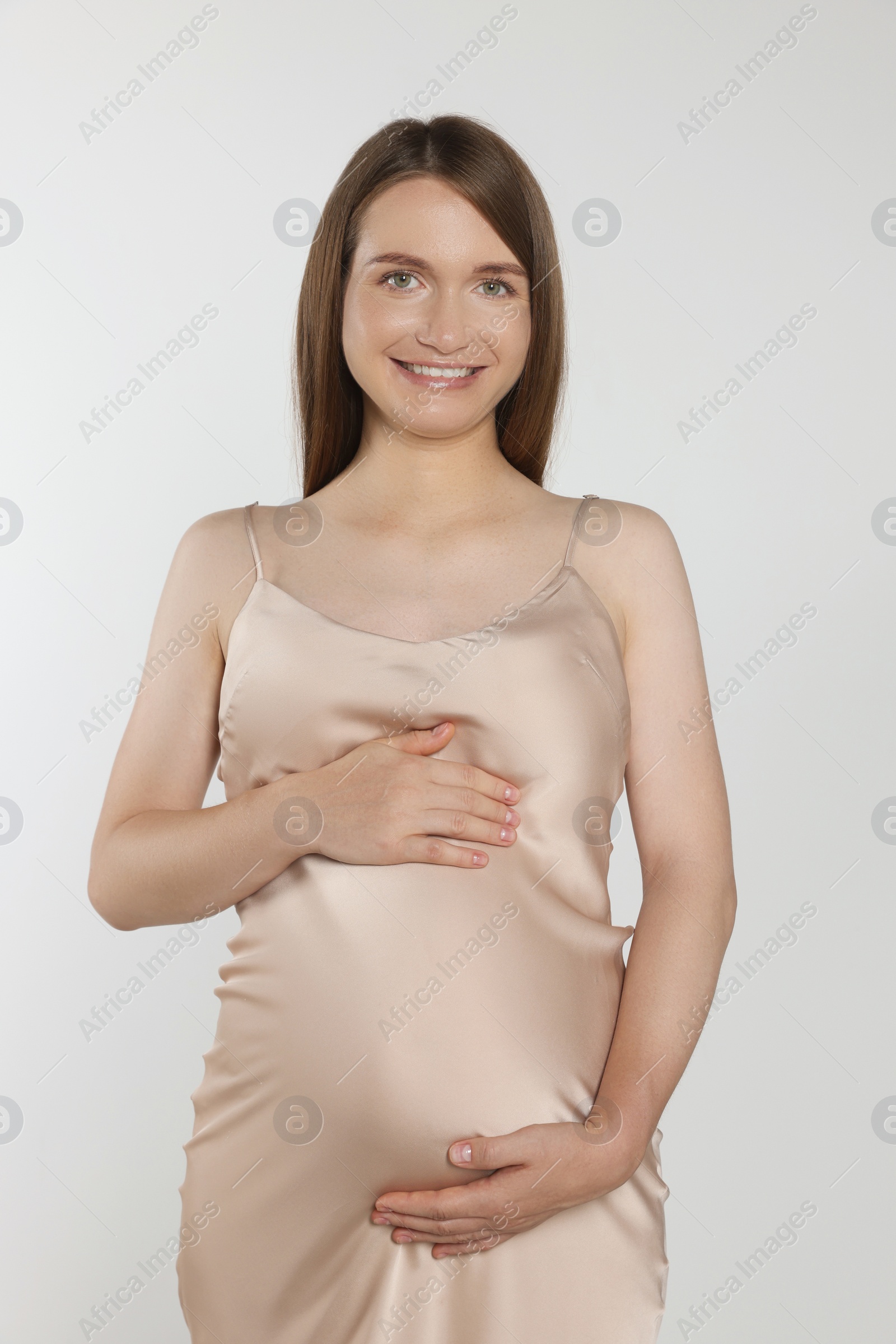 Photo of Happy pregnant woman touching belly on light grey background