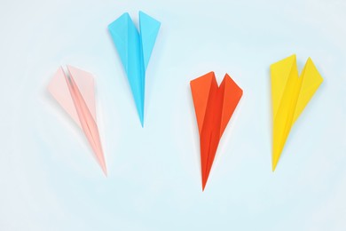 Photo of Handmade colorful paper planes on white table, flat lay