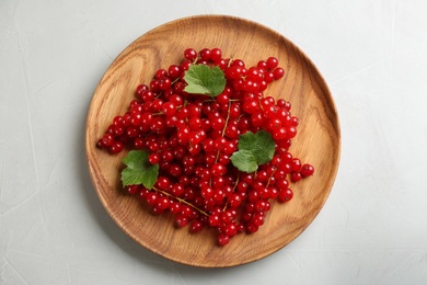 Photo of Delicious red currants and leaves on light table, top view