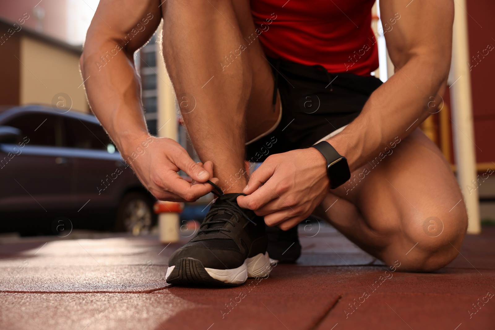 Photo of Man tying shoelaces before training at outdoor gym, closeup