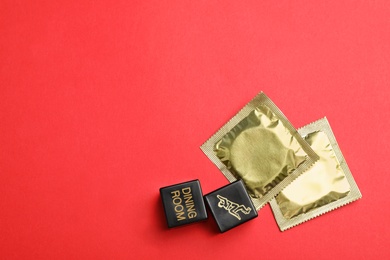 Sex dice and condoms on red background, top view. Space for text