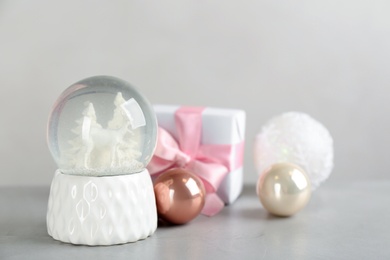 Photo of Beautiful snow globe, gift box and Christmas decor on light grey stone table