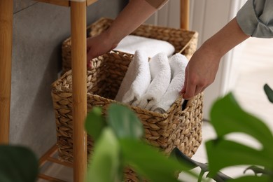 Woman holding storage basket with towels indoors, closeup