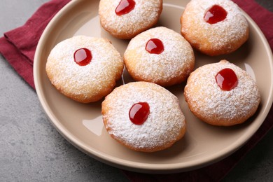 Photo of Hanukkah donuts with jelly and powdered sugar on grey table, closeup
