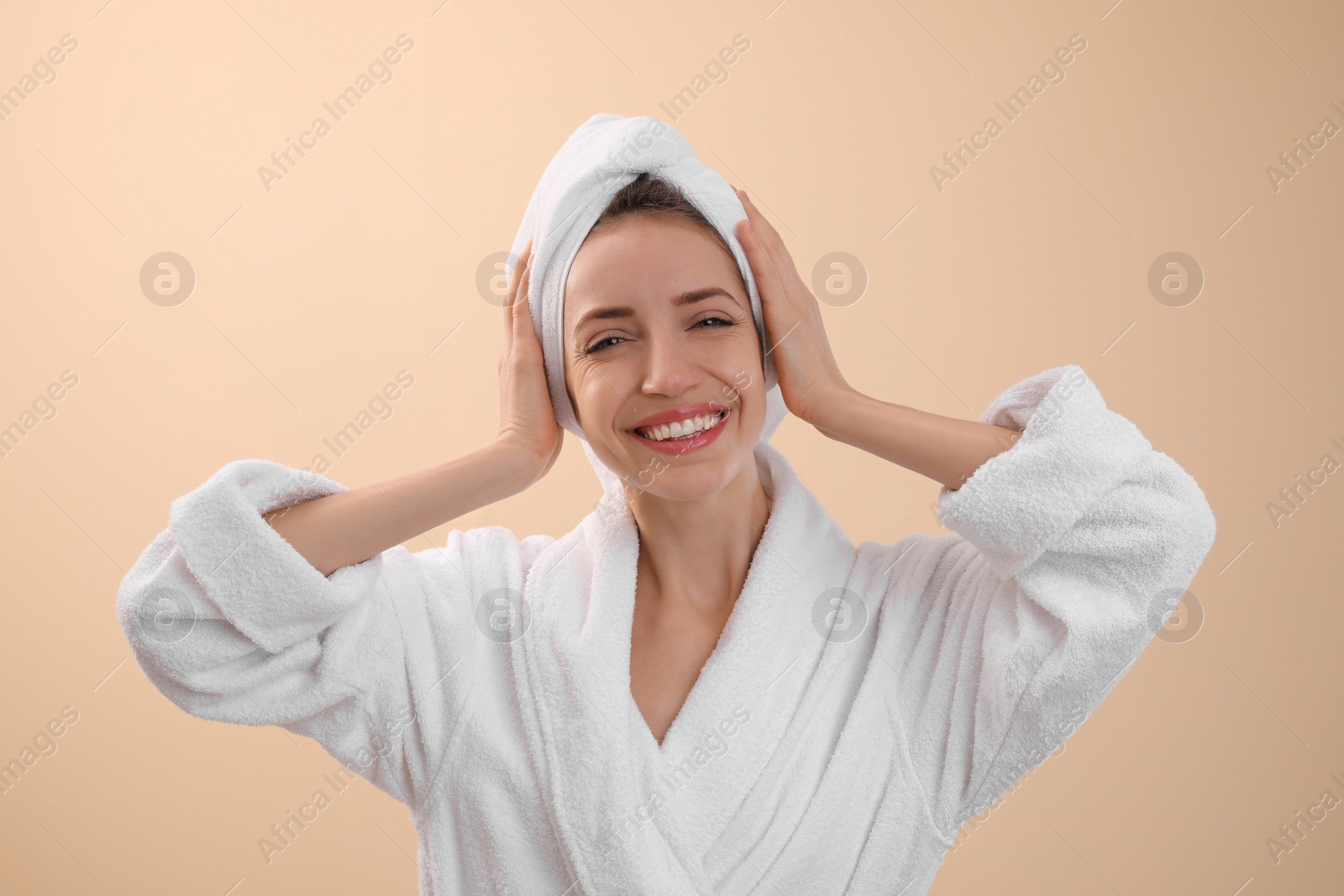 Photo of Beautiful young woman with hair wrapped in towel after washing on beige background