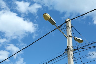 Photo of Street light pole against cloudy sky on sunny day, low angle view