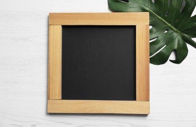 Photo of Blank chalkboard with green leaf on white wooden background, flat lay. Space for text