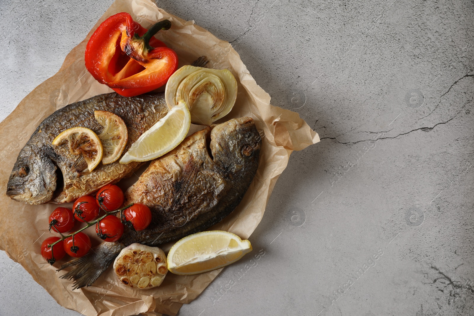 Photo of Delicious dorado fish with vegetables served on light grey table, top view. Space for text