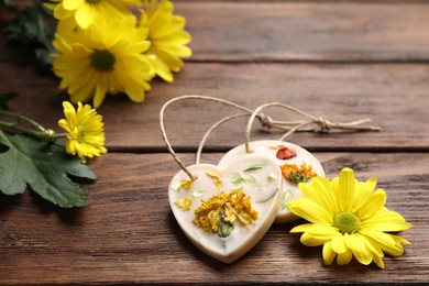 Photo of Scented sachets and flowers on wooden table