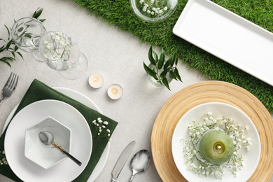 Elegant table setting with green plants on light cloth, flat lay