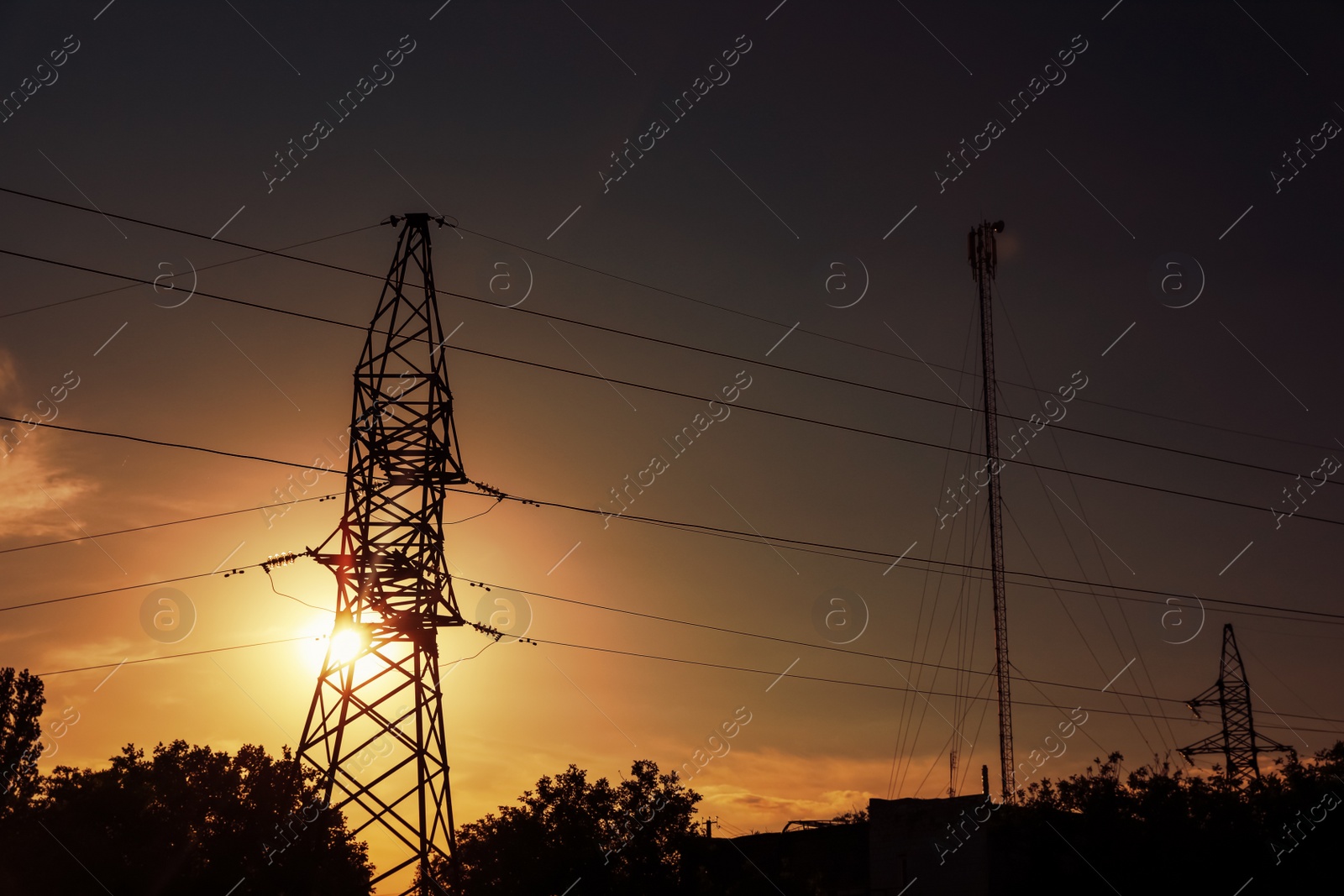 Photo of Silhouettes of high voltage tower and trees in evening