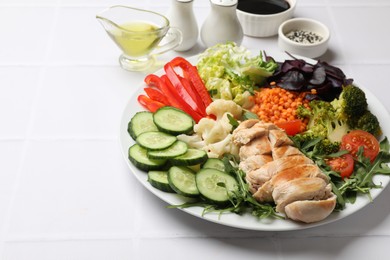 Balanced diet and healthy foods. Plate with different delicious products on white tiled table. Space for text