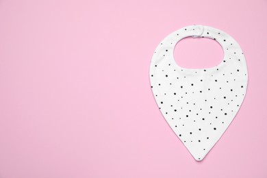 New baby bib on pink background, top view. Space for text