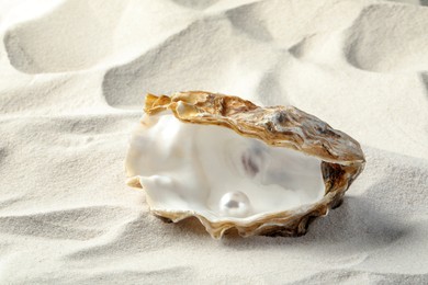 Open oyster with white pearl on sand