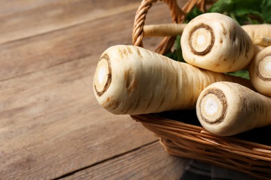 Wicker basket with delicious fresh ripe parsnips on wooden table, closeup. Space for text