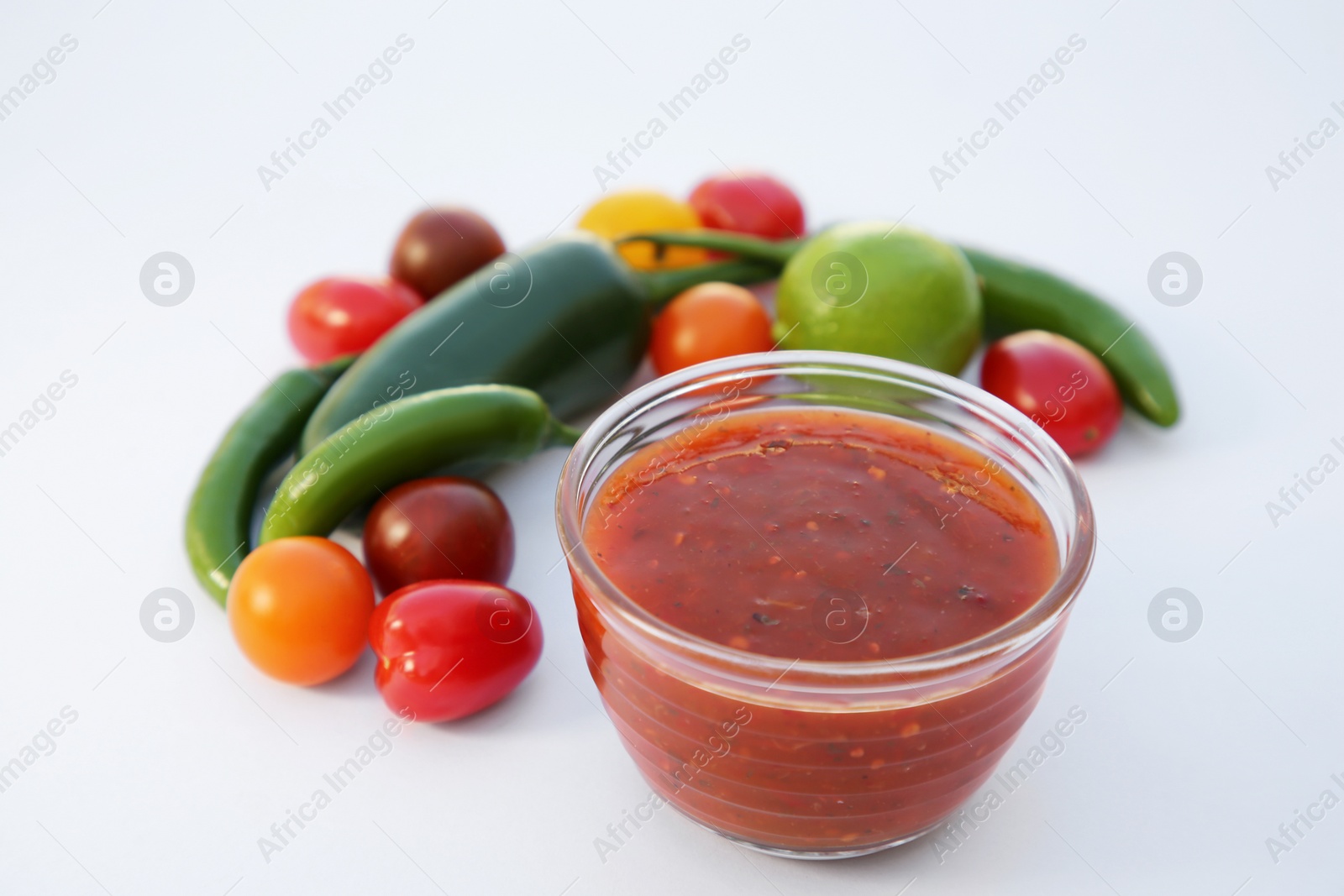 Photo of Bowl with delicious salsa sauce and ingredients on white background, closeup