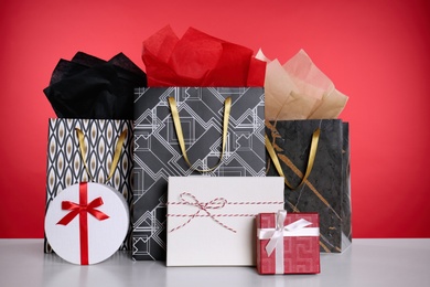 Photo of Shopping paper bags and gift boxes on red background