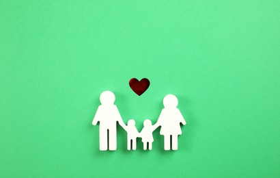 Photo of Family figure and red heart on green background, flat lay
