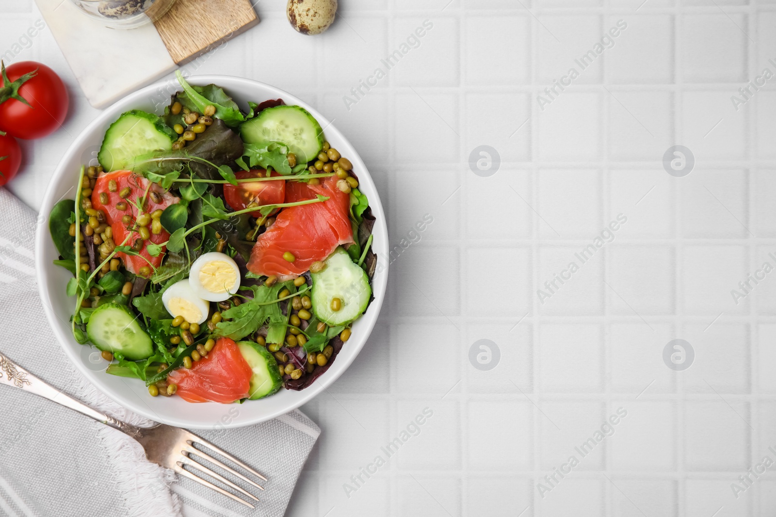 Photo of Bowl of salad with mung beans on white tiled table, flat lay. Space for text