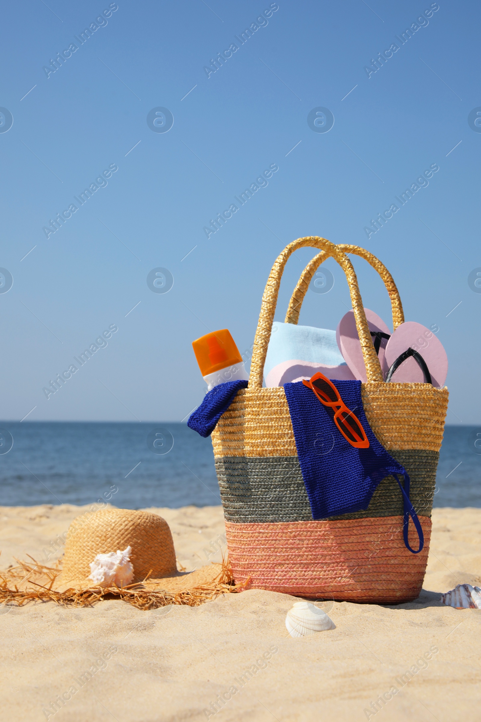 Photo of Bag with beach accessories and hat on sand near sea