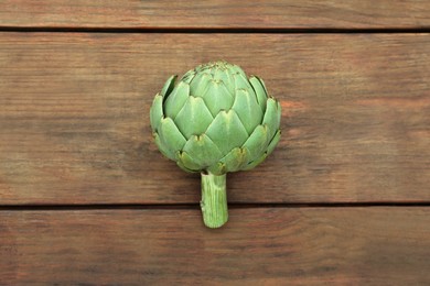 Photo of Fresh raw artichoke on wooden table, top view