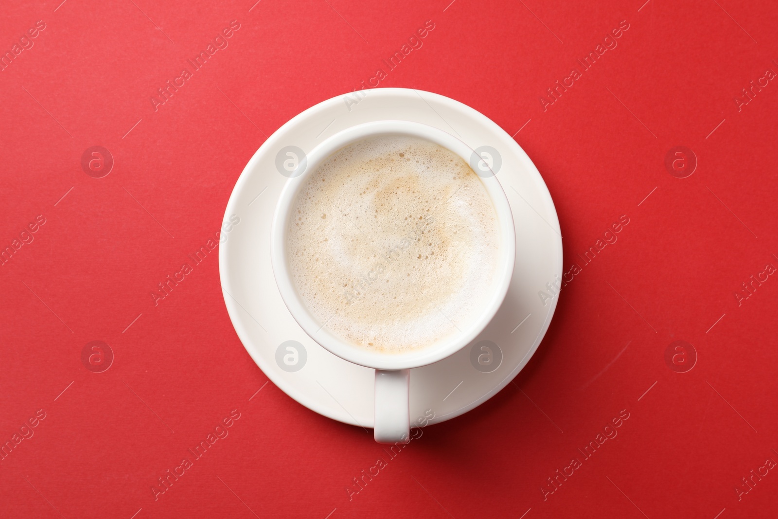 Photo of Cup of aromatic coffee on red background, top view