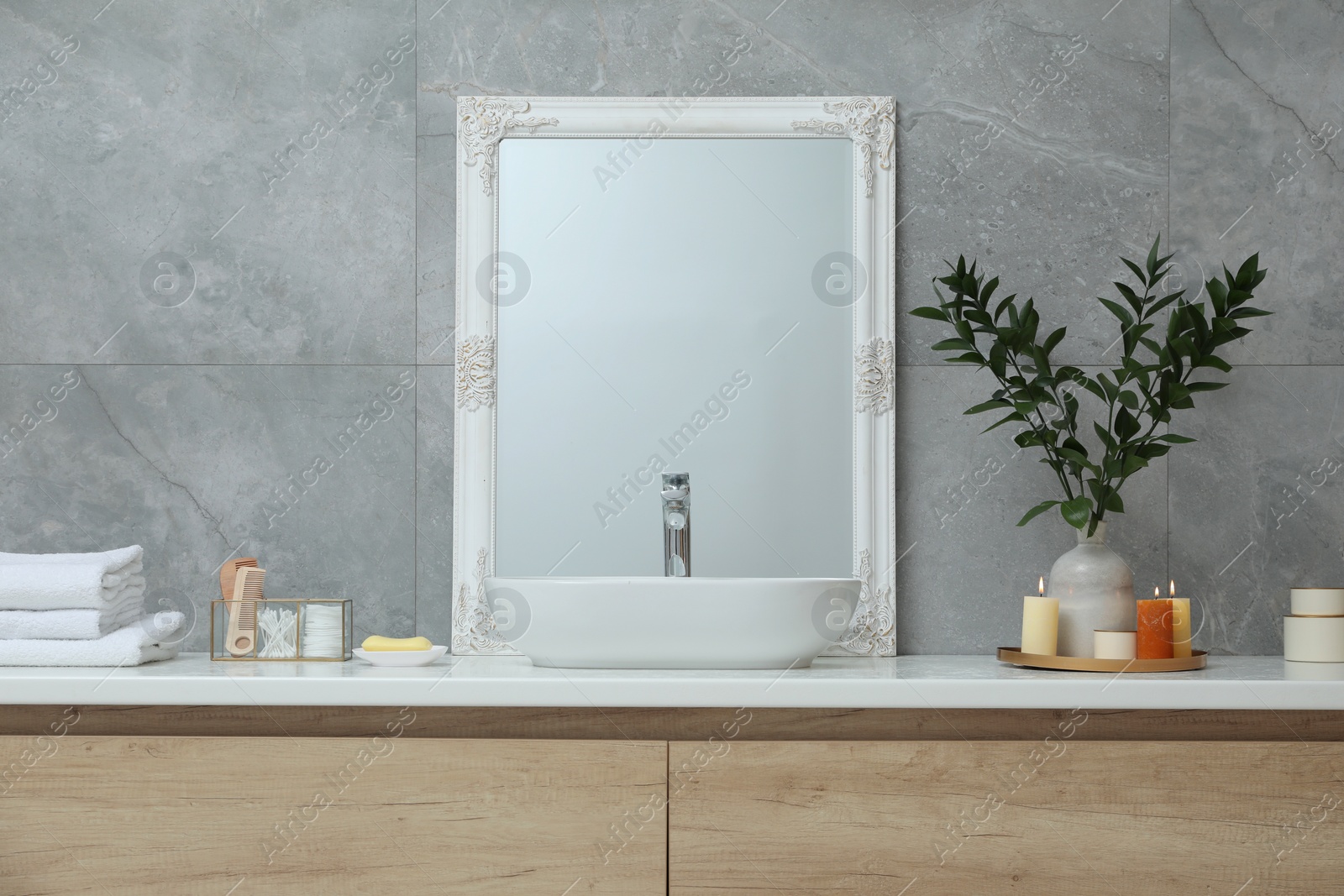 Photo of Beautiful plant in vase and burning candles near vessel sink and mirror on bathroom vanity