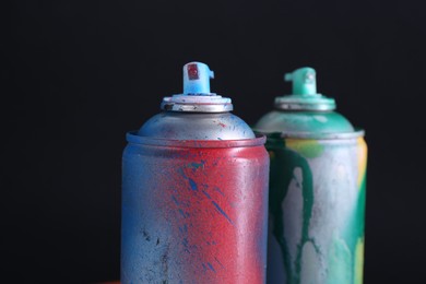 Photo of Two spray paint cans on dark background, closeup