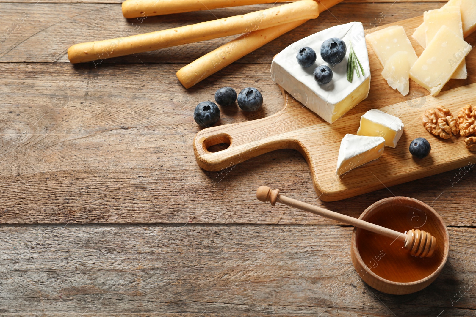 Photo of Different delicious cheeses served on wooden table, space for text