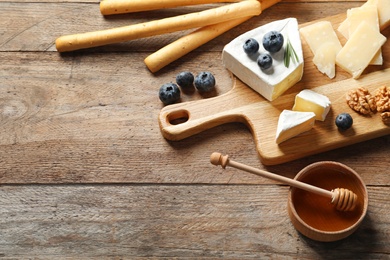 Photo of Different delicious cheeses served on wooden table, space for text