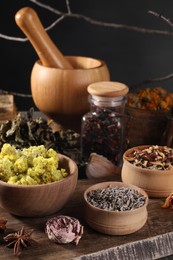 Photo of Many different dry herbs, flowers and mortar with pestle on table