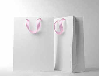 Photo of Paper shopping bags with ribbon handles on white background. Mockup for design