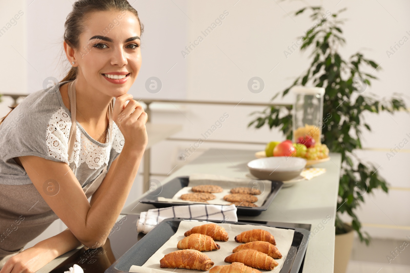 Photo of Young woman with homemade oven baked pastry  in kitchen