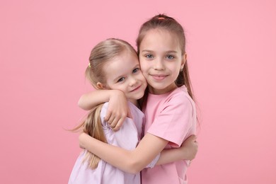 Portrait of cute little sisters on pink background