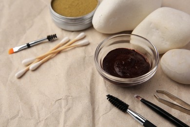 Photo of Eyebrow henna and tools on crumpled paper, closeup
