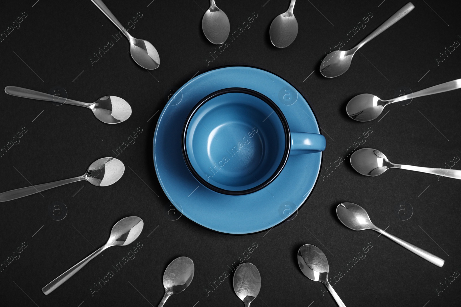 Photo of Flat lay composition with metal spoons and empty cup on black background