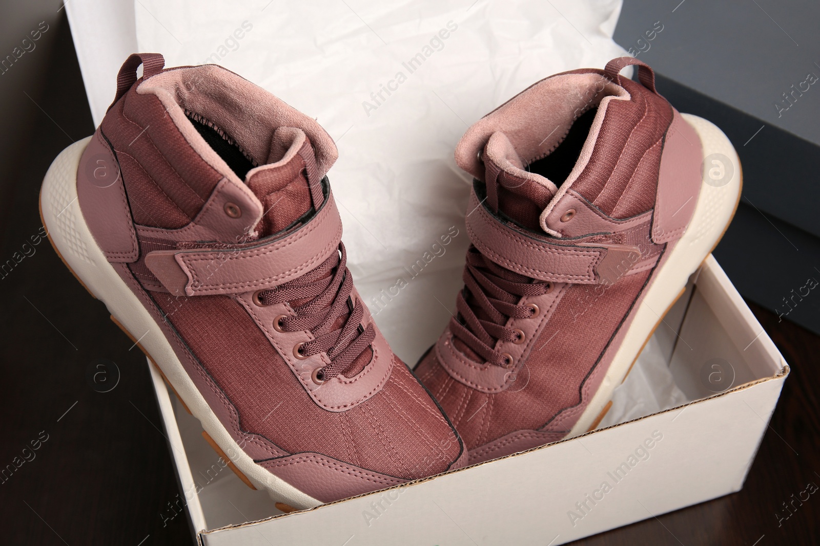 Photo of Pair of stylish kid's sneakers and box on wooden table, closeup