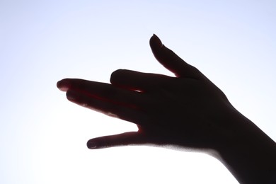 Photo of Shadow puppet. Woman making hand gesture like dog on light background, closeup