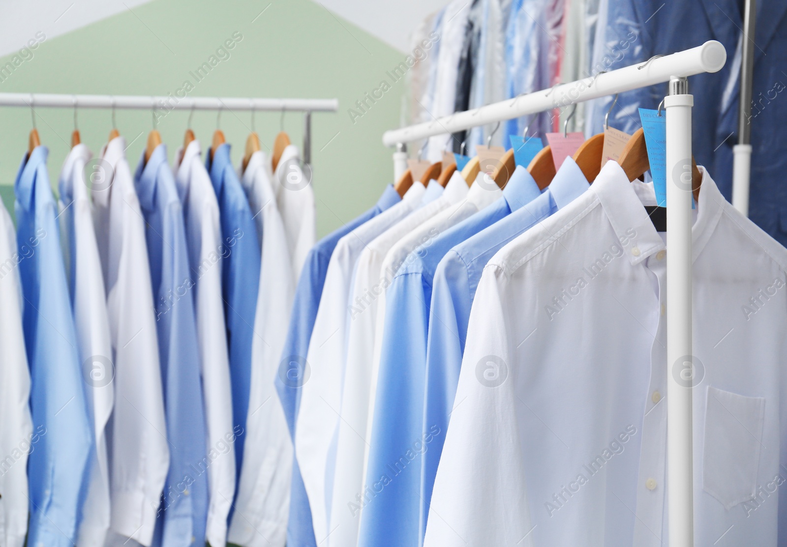 Photo of Racks with clean clothes on hangers after dry-cleaning indoors