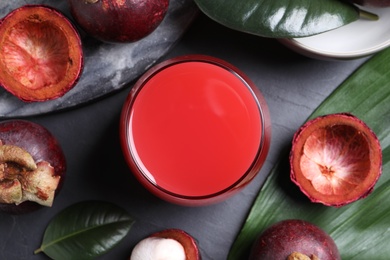 Delicious mangosteen juice and fresh fruits on dark table, flat lay