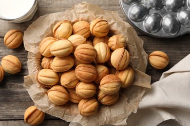 Photo of Bowl of delicious nut shaped cookies on wooden table, flat lay