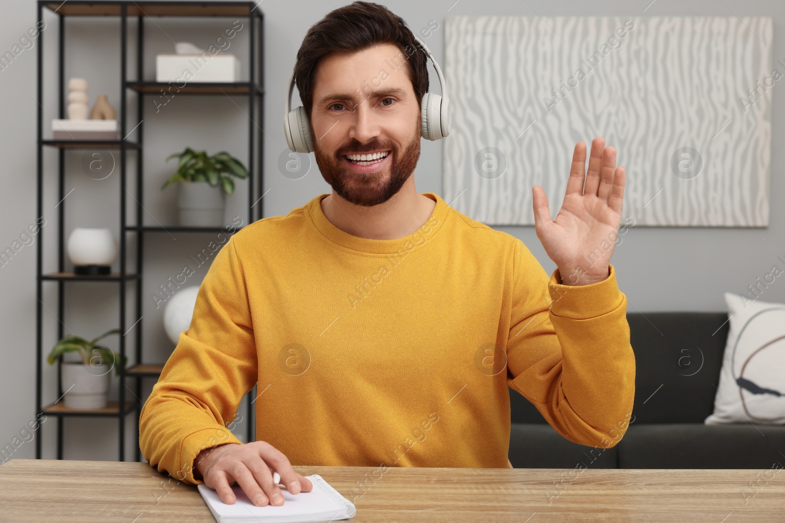 Photo of Stylish man in headphones greeting someone indoors